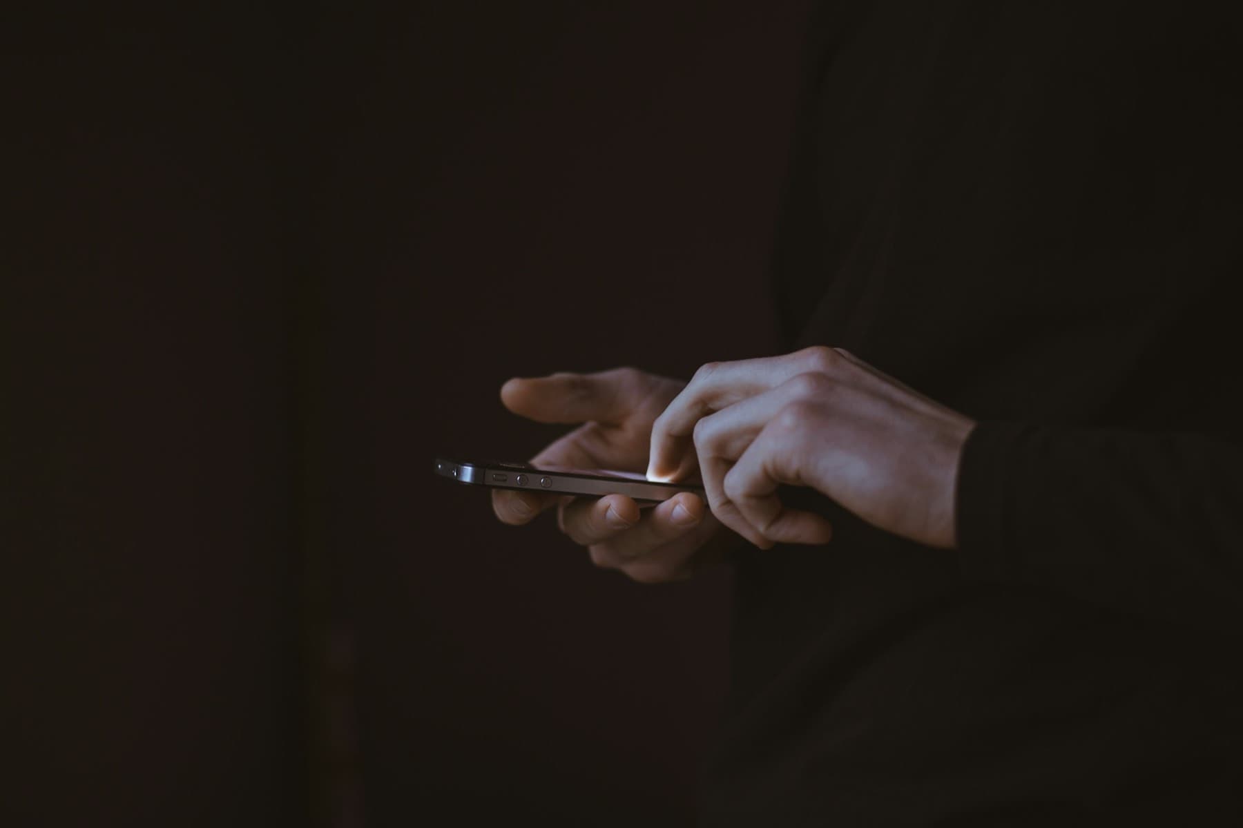 Silhouette of a person holding a smartphone against the light
